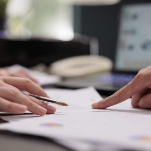 Coworkers analyzing financial report on meeting, hands close up